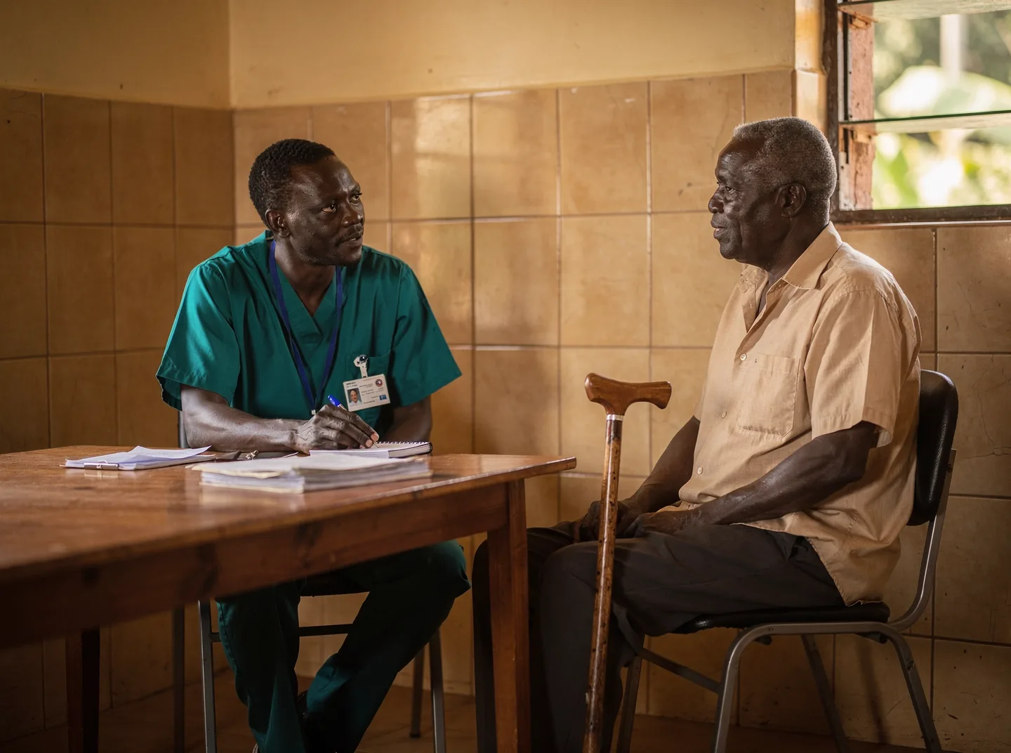 A clinician listening to an older patient in a clinic room