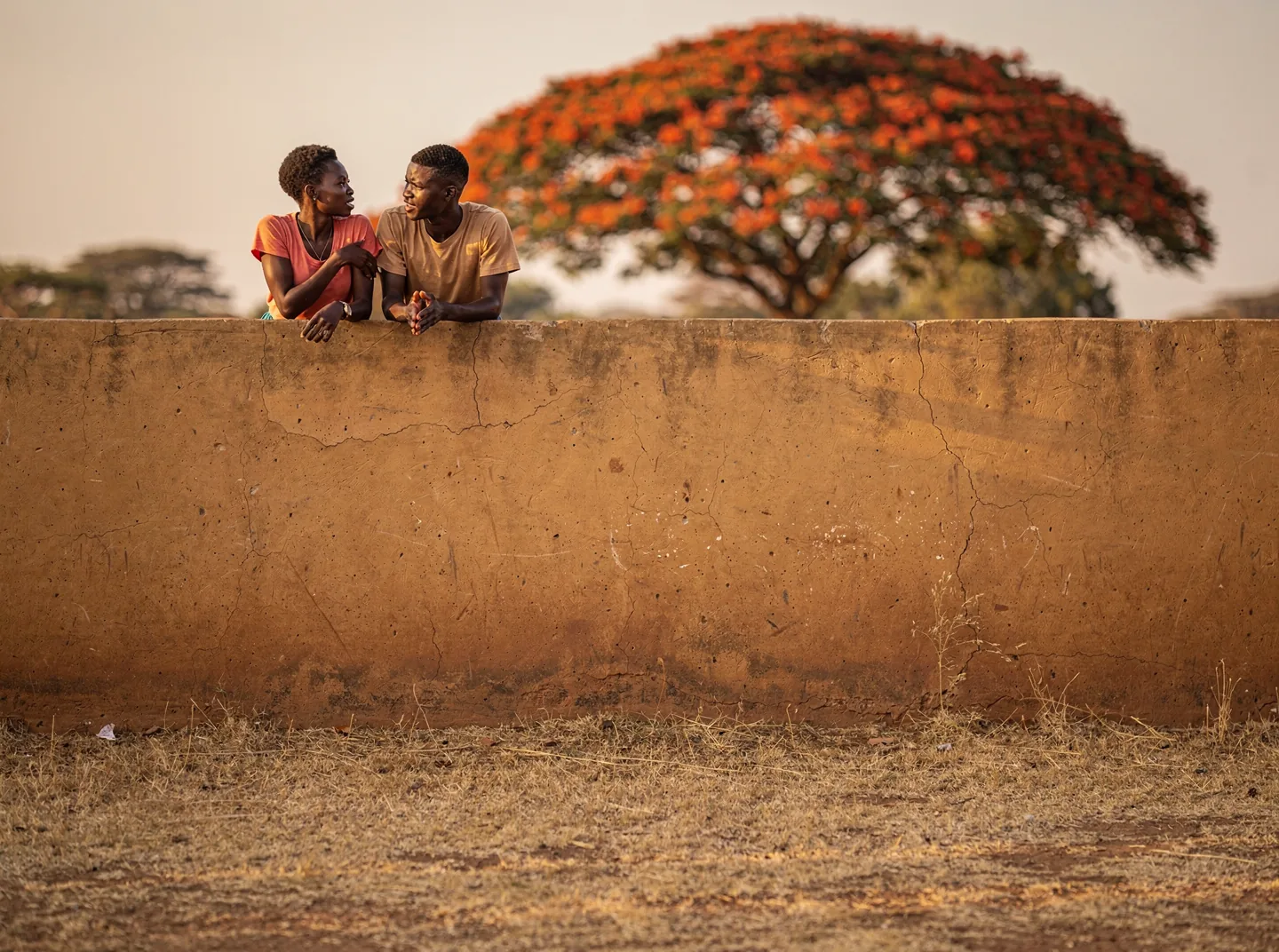 Two young people talking at the edge of a school field